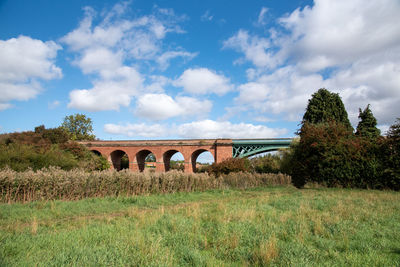 Arch bridge on field against sky