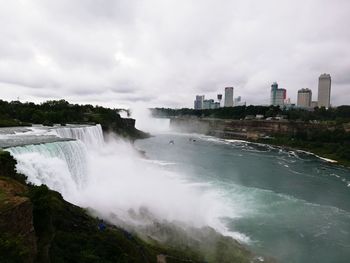 Scenic view of waterfall against sky in city