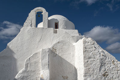 Low angle view of cross amidst buildings against sky