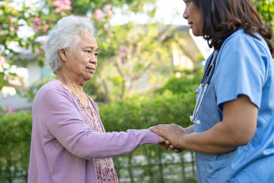 Doctor help and care asian senior woman use walker with strong health while walking at park 