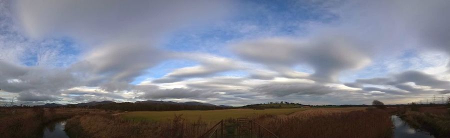 Panoramic view of agricultural field against sky