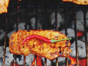 High angle view of meat and red chili pepper on barbecue grill