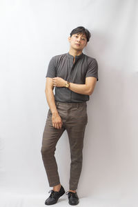 Portrait of young man standing against wall