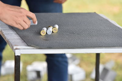 Cropped hand of person holding bullet on table by man