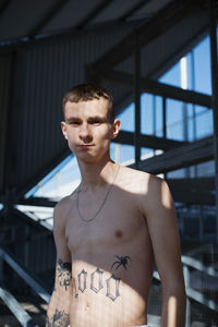 Portrait of shirtless young man standing indoors