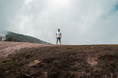 Rear view of man standing on field against sky