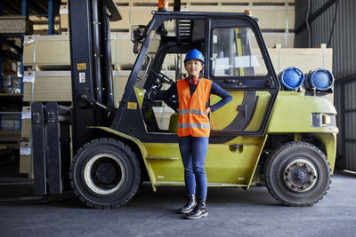 Portrait of confident female worker at forklift in factory