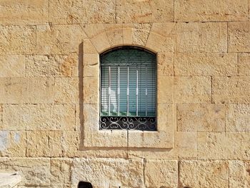 Old rustic vintage window green blind on stone wall.