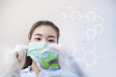 Low angle view of scientist analyzing leaves in petri dish against white background