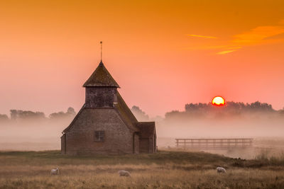 Church on field against sky during sunset