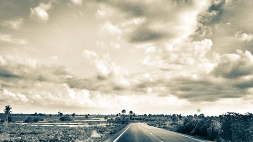 Road passing through landscape against cloudy sky