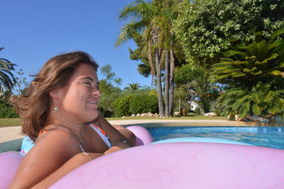 Beautiful young woman floating on a lilo in a swimming pool on a bright and sunny summer day