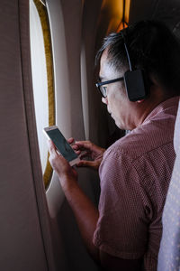 Side view of man using mobile phone in airplane