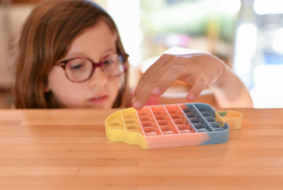 A girl plays with a colorful antistress sensory toy push pop it