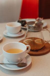 Ceramic white cup and teapot with orange tea in the cafeteria