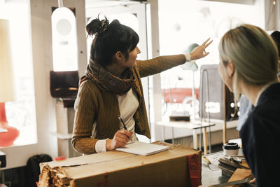 Female customer discussing with owner at repair shop