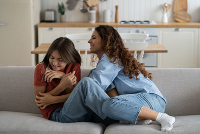 Joyful mother and daughter having fun and laughing while spending time together at home