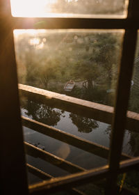 View of a small lake and wooden boat from a tree house window