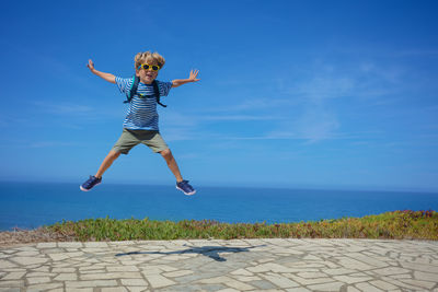 Full length of young woman jumping against sky