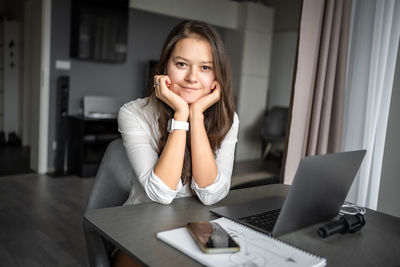 Portrait of young woman using laptop at home