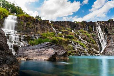 Scenic view of waterfall against sky