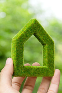 Cropped image of person holding green house shape