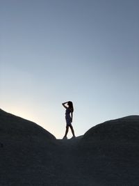 Side view of woman standing on land against clear sky