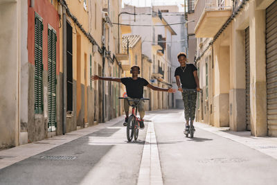 People riding bicycle on street amidst buildings in city