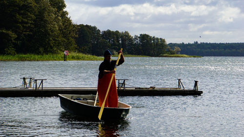 Man standing on boat in lake against sky