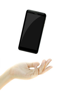 Close-up of hand using smart phone against white background