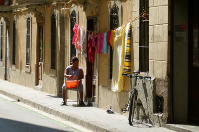 Woman sitting on sidewalk by building