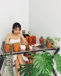 Young woman sitting by potted plant on table