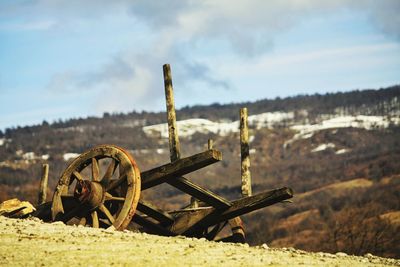 Abandoned wagon wheel on field against sky