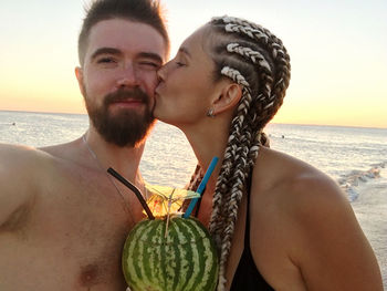 Couple kissing on beach against sky