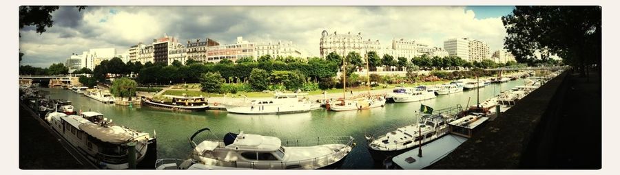 Boats in harbor against cloudy sky