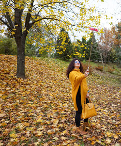 Full length of woman doing selfie while standing in park during autumn