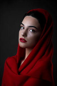 Portrait of beautiful young woman against black background