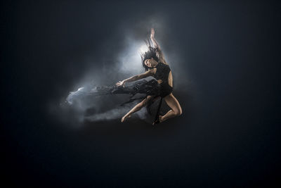 Low angle view of woman dancing against black background