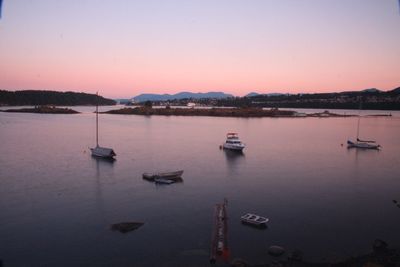 Boats in sea against sky during sunset