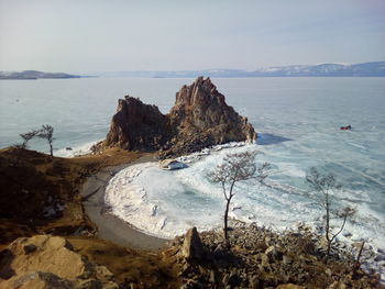 Scenic view of rocks by frozen sea against sky