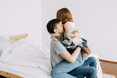 Home love story, guy and girl hug and kiss in the bedroom of the house