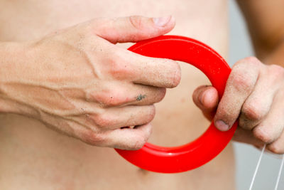 Midsection of man holding red plastic equipment at beach