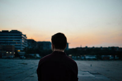 Rear view of man looking at city during sunset