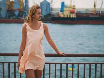 Close-up of young woman standing on railing against sea