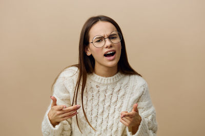 Portrait of young woman standing against gray background