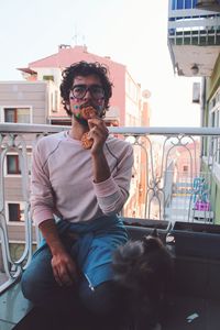 Portrait of man with dog sitting against built structure