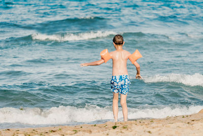 Rear view of shirtless boy on beach