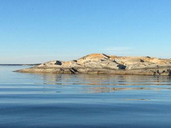 Surface level of rocks by sea against clear sky