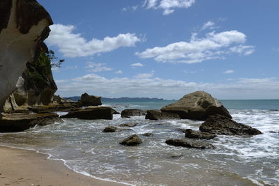 Rock formation on beach against sky