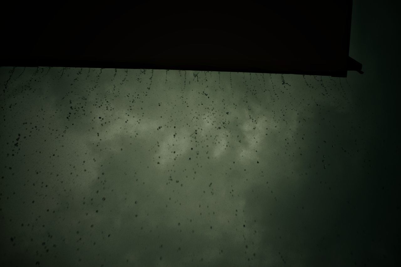 LOW ANGLE VIEW OF WET GLASS WINDOW AT NIGHT